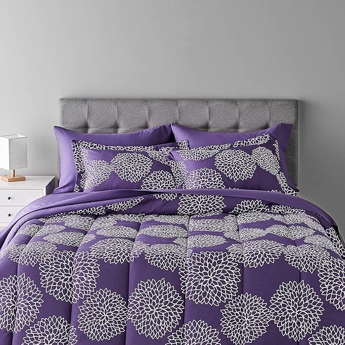 Purple floral patterned bedding set on a bed with a gray headboard.