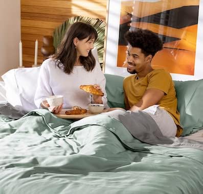 Two people sitting on a bed eating breakfast together.