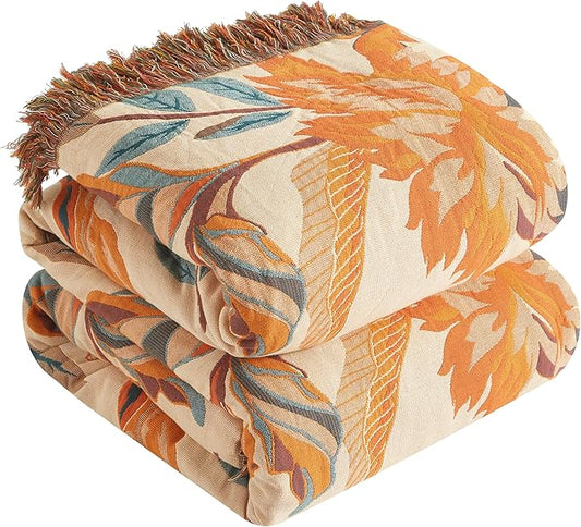 Folded floral-patterned blanket with orange, beige, and brown colors on a white background
