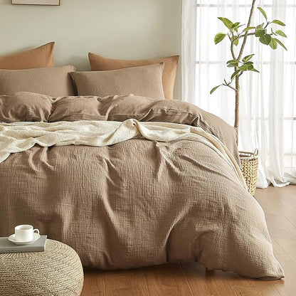 Beige textured duvet cover set on a bed with pillows and a plant in the background.