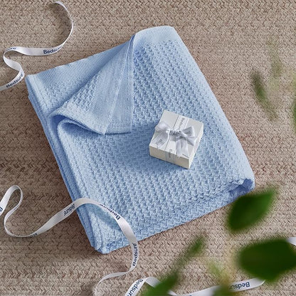 Blue textured blanket with a white gift box on a beige carpet