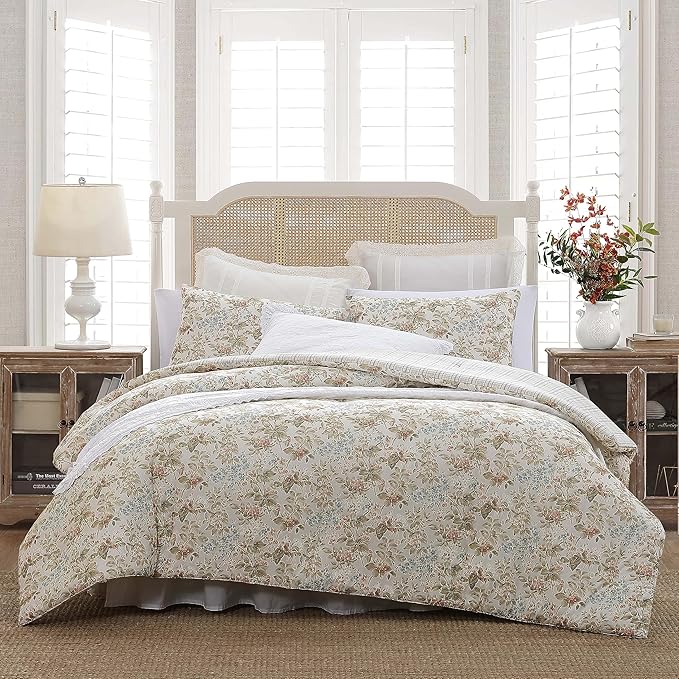 Floral comforter set on a bed in a bedroom with wooden nightstands and a lamp.