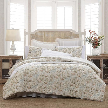 Floral comforter set on a bed in a bedroom with wooden nightstands and a lamp.