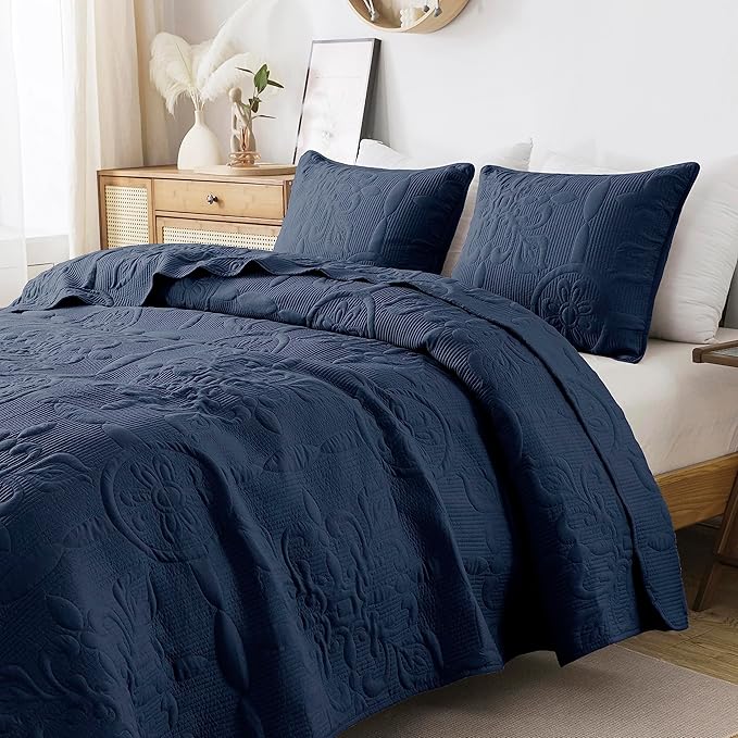 Navy blue textured comforter set on a bed in a bedroom setting.