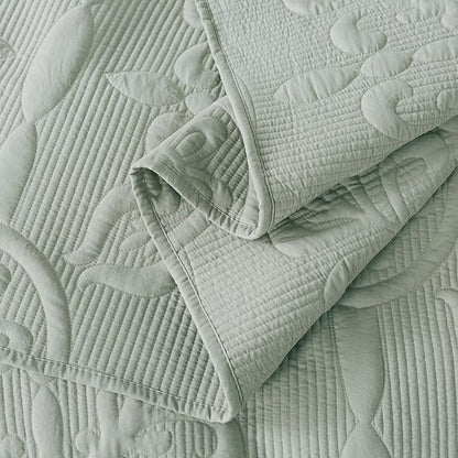 Light green quilt with textured pattern on a matching fabric background