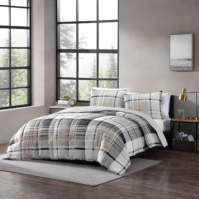 Plaid bedding set on a bed in a room with large windows and a painting on the wall.