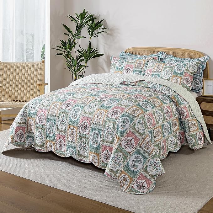 Patterned quilt and pillow set on a bed in a bedroom with a plant and chair.