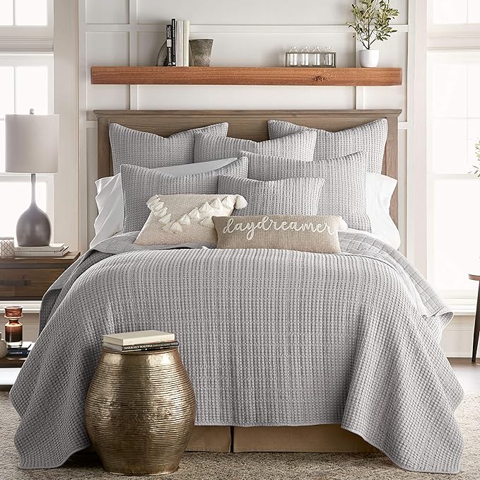 Gray textured comforter set on a bed with pillows in a bedroom setting.