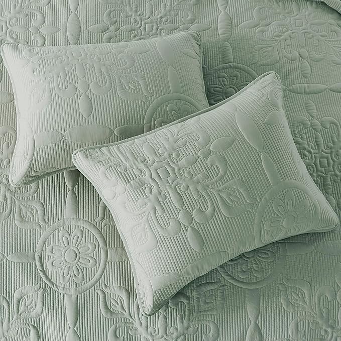 Two textured green pillows on a matching fabric background
