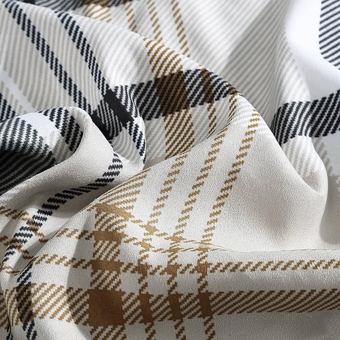Close-up of plaid fabric with brown, black, and white patterns.