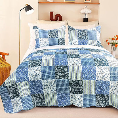 Bed with blue patchwork quilt and pillows in a bedroom setting.