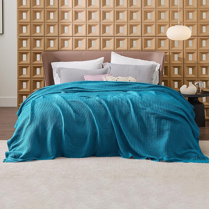Bed with blue comforter and pillows against a geometric wall panel