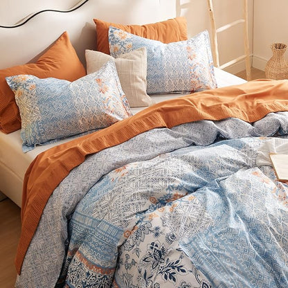 Bed with patterned bedding and pillows in orange, blue, and beige tones.