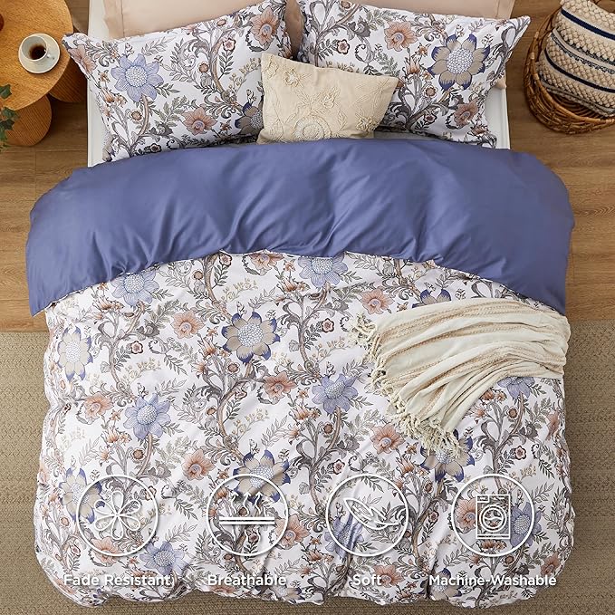 Floral patterned bedding set with blue comforter on a bed in a bedroom.