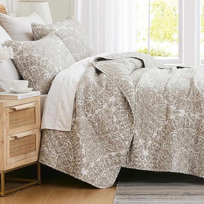 Bed with paisley patterned bedding in a bright bedroom
