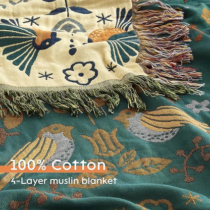 Decorative 4-layer muslin blanket with intricate patterns and fringes on a green background.